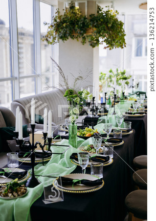Elegant black and green tablescape with candles, place settings and glassware 136214753