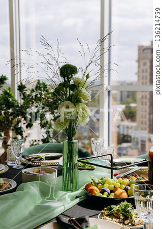 Green floral centerpiece on elegant banquet table with city view, natural light 136214759