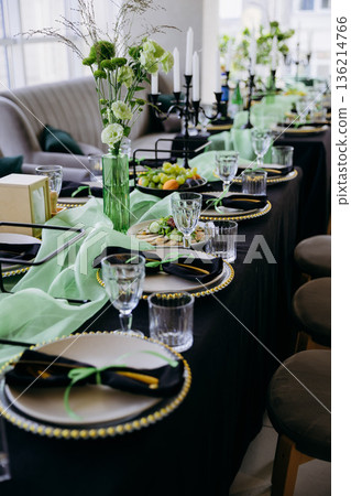 Elegant black and green tablescape with candles, place settings and glassware 136214766