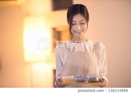 Middle-aged woman carrying dinner to the table Middle-aged woman carrying dinner to the table 136214898
