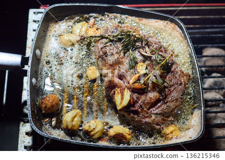 barbecue party, close-up image of grilling steaks, the meat is stewed in butter with garlic and thyme, spiking pieces of meat on the grill, various vegetables, lots of smoke 136215346