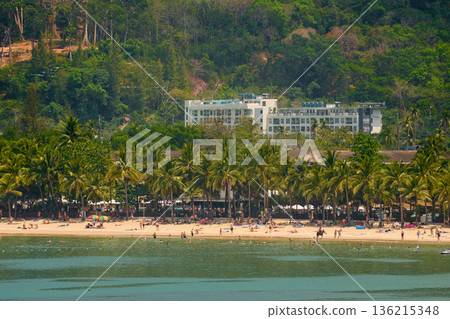 Thailand's coast on a sunny day, villas and hotels among palm trees on a hill, people on a jet ski, a yacht off the coast Thailand's coast on a sunny day, villas and hotels among palm trees on a hill, people on a jet ski, a yacht off the coast 136215348