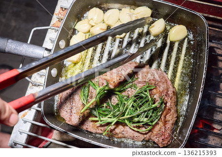 barbecue party, close-up image of grilling steaks, the meat is stewed in butter with garlic and thyme, spiking pieces of meat on the grill, various vegetables, lots of smoke barbecue party, close-up image of grilling steaks, the meat is stewed in butter with garlic and thyme, spiking pieces of meat on the grill, various vegetables, lots of smoke 136215393