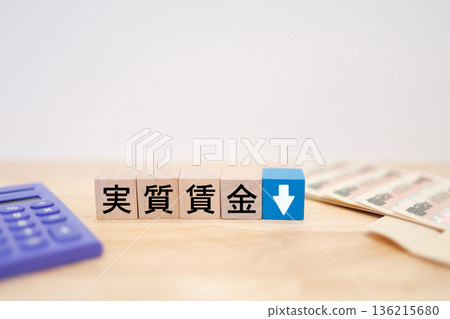 An image of a banknote with a downward arrow indicating a decline in real wages. An image of a banknote with a downward arrow indicating a decline in real wages. 136215680