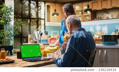 Chroma key laptop with retired man checking display at the table in rustic kitchen, relaxed senior people spending their cozy lifestyle at home. Serving coffee and pastry. Camera A. Chroma key laptop with retired man checking display at the table in rustic kitchen, relaxed senior people spending their cozy lifestyle at home. Serving coffee and pastry. Camera A. 136216418
