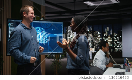 Silicon Valley company IT staff members laughing in office, developing apps with AI. System administrators sharing jokes while waiting for artificial intelligence to debug applications 136216433