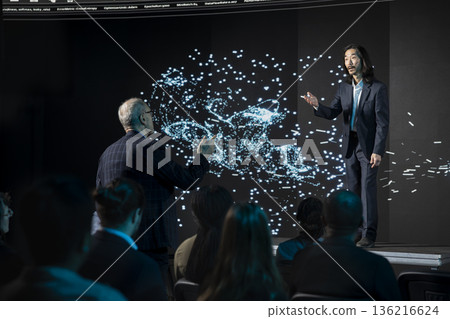 Senior businessman giving suggestions during LLM in-house debate in auditorium, analyzing AI systems as a team. Male standing up and asking questions, tech diversification. 136216624