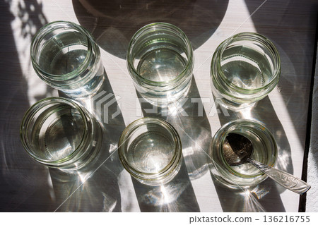 Top view of six clear glasses filled with water prepared for dissolving food coloring for the easter egg dyeing process. Top view of six clear glasses filled with water prepared for dissolving food coloring for the easter egg dyeing process. 136216755
