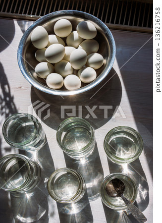 Eggs in bowl with water jars for easter egg dyeing in sunlight top view Eggs in bowl with water jars for easter egg dyeing in sunlight top view 136216758