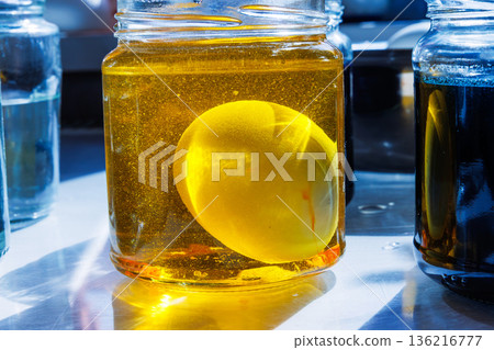 Close up of egg soaking in yellow dye jar for easter egg coloring 136216777