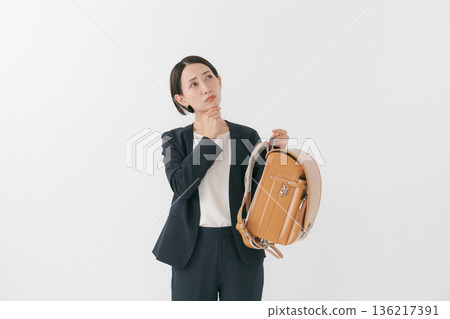 A woman with a thinking expression holding a school bag A woman with a thinking expression holding a school bag 136217391