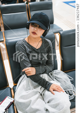 一位女士在機場聽音樂。照片由關西國際機場(KIX)提供。 一位女士在機場聽音樂。照片由關西國際機場(KIX)提供。 136217487