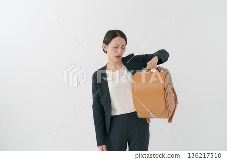 一位母親因為背書包而感到煩惱。 一位母親因為背書包而感到煩惱。 136217510