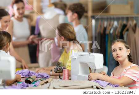 Girl child sews during practical lesson at school of young fashion designers and tailors 136218943