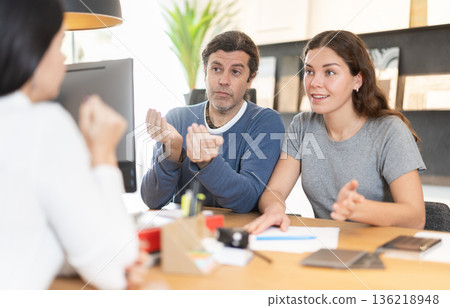 Married couple discusses the terms of purchasing a new kitchen set with furniture store manager 136218948