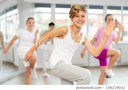 Group of teenagers learn to dance hip-hop and other modern dances in spacious dance studio 136219032