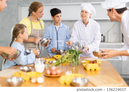 Team of positive teenagers and female chef at cooking classes. Learn to beat raw eggs 136219037