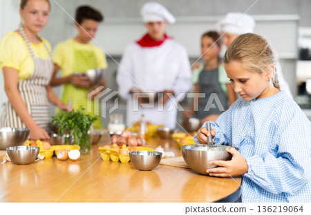 Interested tween girl attending group culinary classes for children Interested tween girl attending group culinary classes for children 136219064