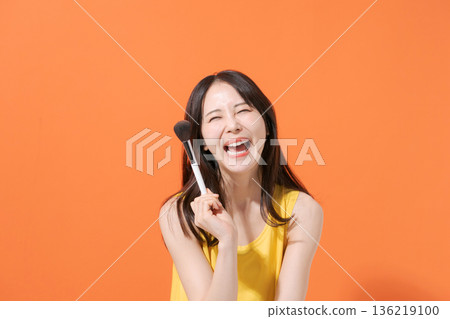 Smiling woman holding makeup brushes Smiling woman holding makeup brushes 136219100
