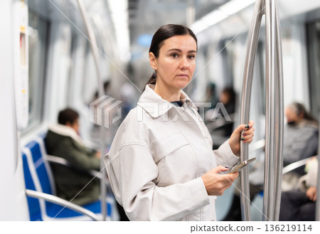 Woman using smartphone while traveling in subway car 136219114