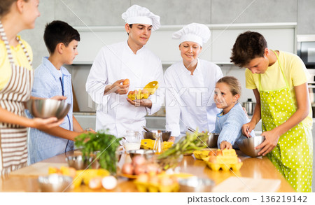 Positive professional chefs in white uniform conducting culinary masterclass for tweens 136219142