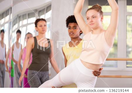 Teenage girl practicing ballet positions in pair with boy in dance studio 136219144