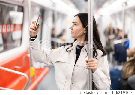 Woman in metro carriage points phone camera at an information board 136219169