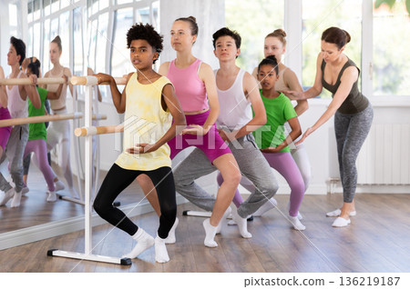 Woman teacher corrects teenagers in plie movement 136219187