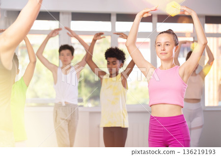 Teen girl participating in beginner group ballet class 136219193