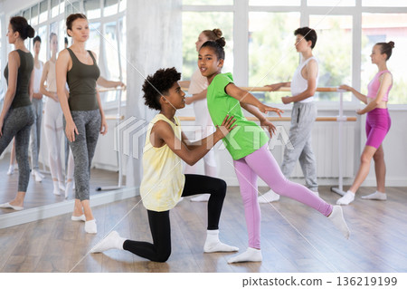 Teenage boy and girl doing together arabesque position of ballet during choreography classes 136219199