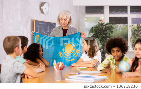 Female teacher showing kazakh flag to kids in geography class 136219230