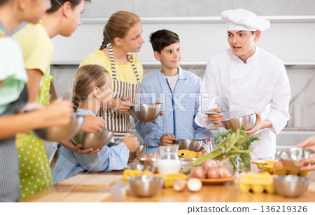 Friendly young chef running culinary courses for group of children 136219326