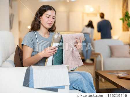 Young woman absorbing textile samples for furniture 136219346
