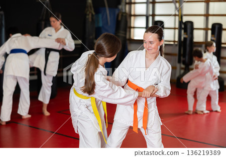 Children athletes in pair conduct training battle in oriental fighting technique 136219389