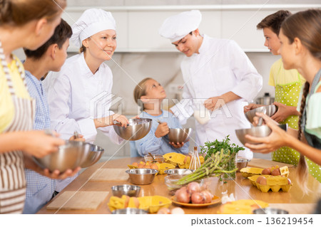 Young guy and adult woman cook teaches group of children to cook Young guy and adult woman cook teaches group of children to cook 136219454
