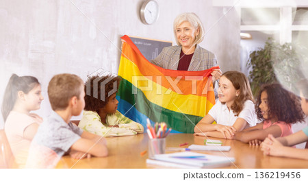 Female teacher showing rainbow flag to kids in geography class 136219456