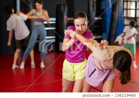 Purposeful engrossed teen girls train during self-defense fight training session in gym Purposeful engrossed teen girls train during self-defense fight training session in gym 136219460