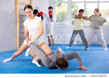 Teenage girl practicing painful armlock in sparring with instructor at self defence training Teenage girl practicing painful armlock in sparring with instructor at self defence training 136219470