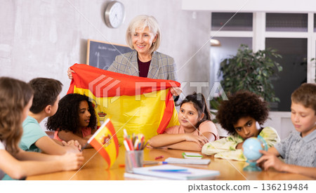 Female teacher showing spanish flag to kids in geography class Female teacher showing spanish flag to kids in geography class 136219484