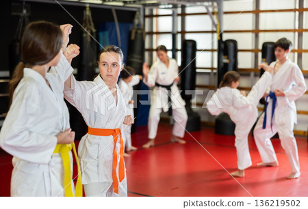 Child girl and tutor train to perform defensive karate installations and attacking combat techniques Child girl and tutor train to perform defensive karate installations and attacking combat techniques 136219502