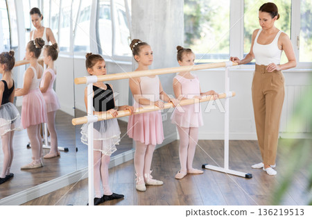 Woman teacher corrects group of girls in first position Woman teacher corrects group of girls in first position 136219513
