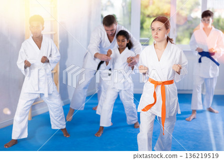 Tween girl practicing punches during group martial arts workout Tween girl practicing punches during group martial arts workout 136219519