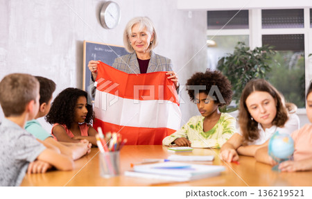 Female teacher showing austrian flag to kids in geography class Female teacher showing austrian flag to kids in geography class 136219521