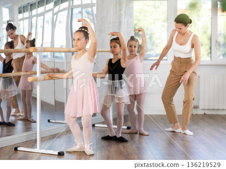 Woman teacher corrects girls in plie movement 136219529