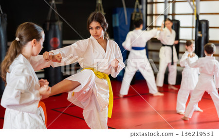 Teenage girls in white kimono at karate lesson 136219531