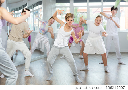 Male boy student repeats movements of unrecognizable teacher during group modern dance class. Male boy student repeats movements of unrecognizable teacher during group modern dance class. 136219607