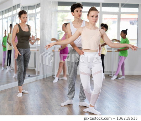 Teenage girl and boy practicing plie position of ballet in dance studio Teenage girl and boy practicing plie position of ballet in dance studio 136219613
