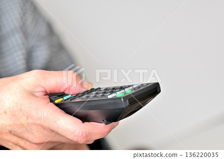 Senior woman operating a TV remote control 136220035