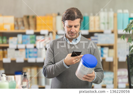 Man in pharmacy scans QR code on infant formula product Man in pharmacy scans QR code on infant formula product 136220056