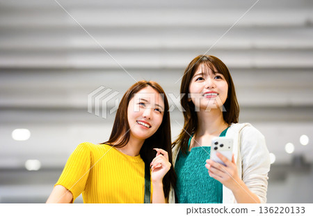 A friend looking at a smartphone at the airport. Photo courtesy of Kansai International Airport (KIX) 136220133